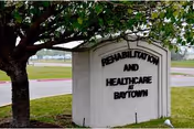 Exterior view of a facility sign for Rehabilitation and Healthcare at La Crescent beside a tree.
