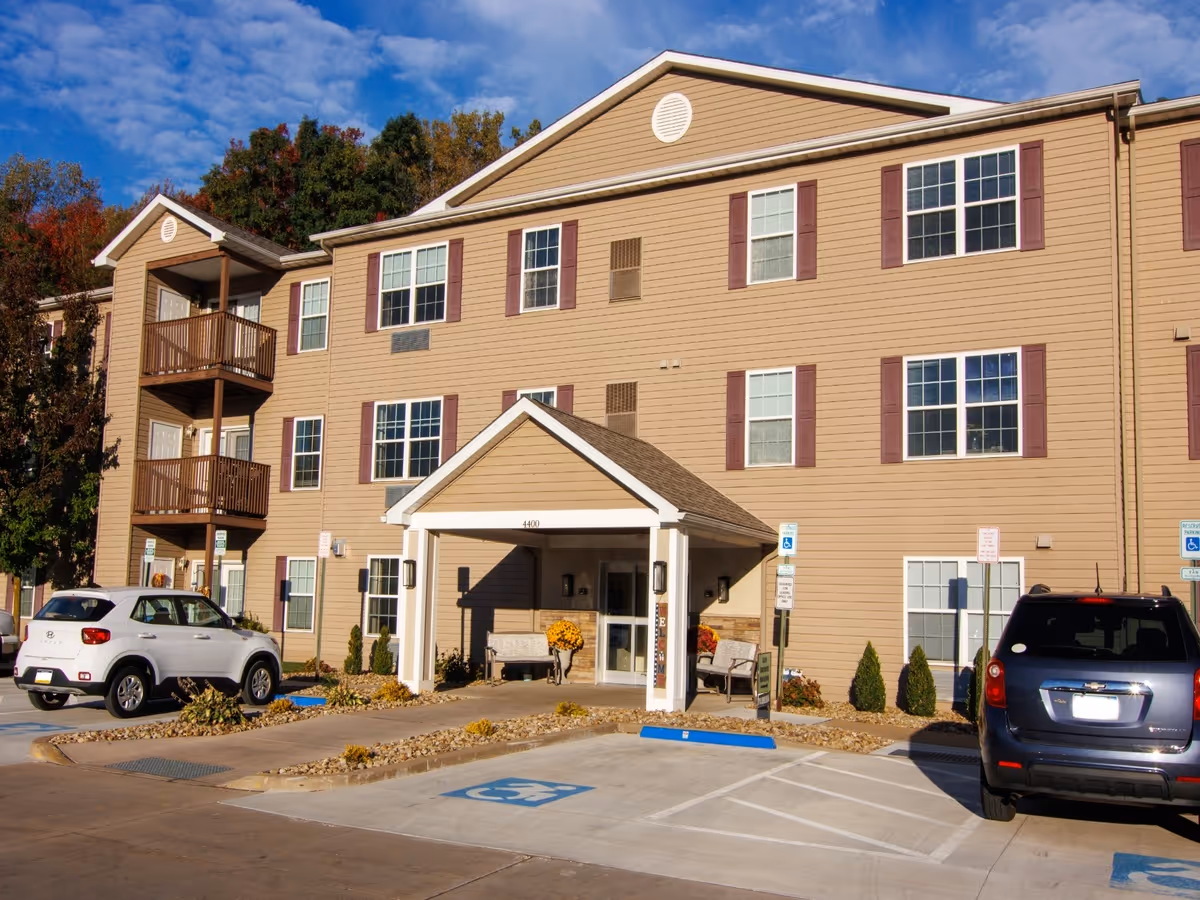 Exterior view of Harborcreek Senior Apartments with an entry canopy and parked cars.