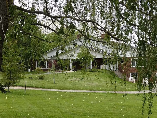 Brick senior living facility facade with a manicured lawn and trees