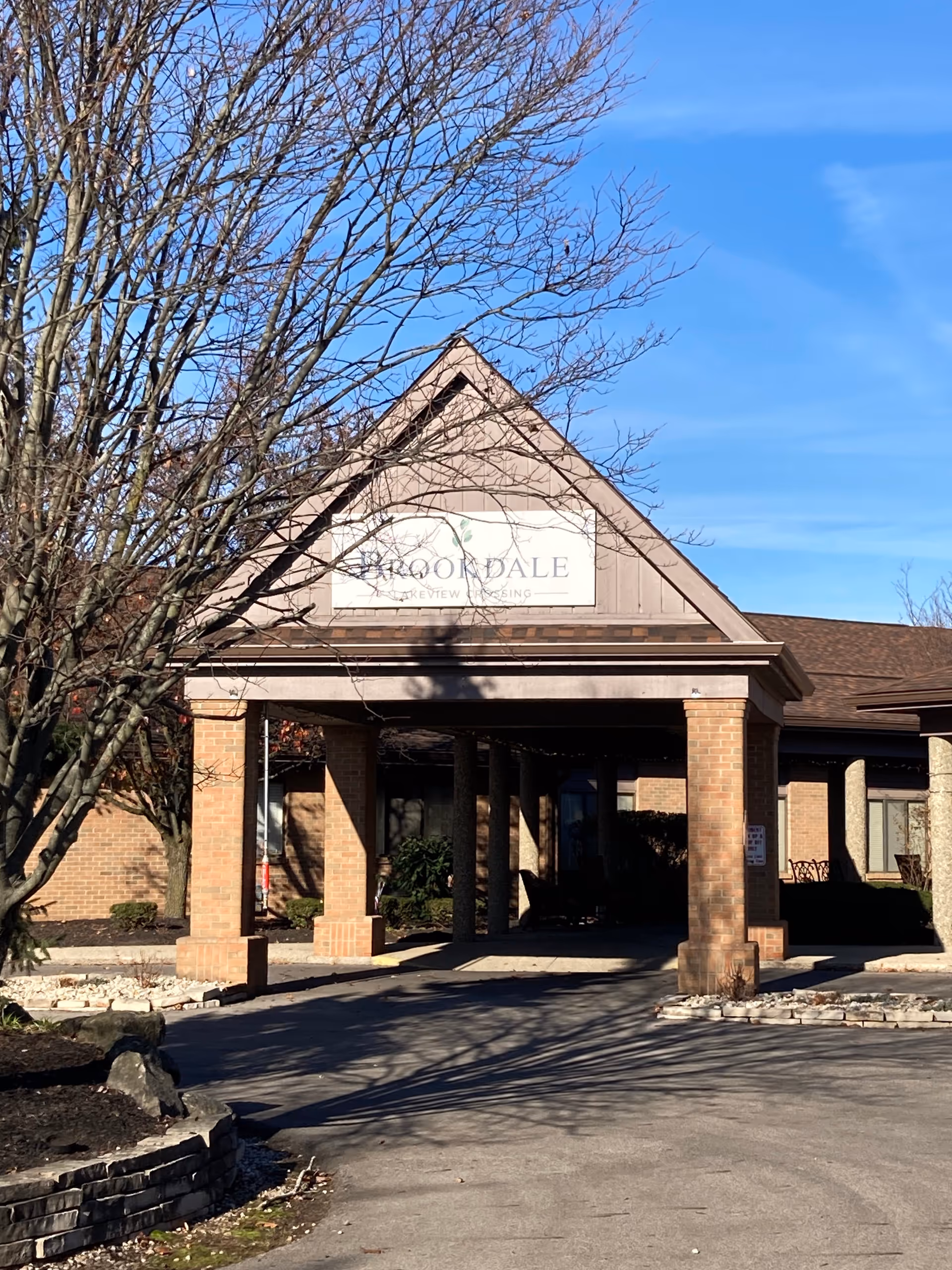 Brookdale Lakeview Crossing brick entrance with a covered porte-cochere and leafless trees.