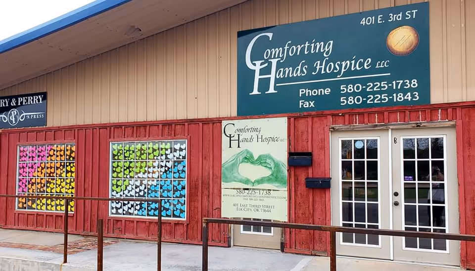Front exterior of a red building showing Comforting Hands Hospice sign and colorful window art.