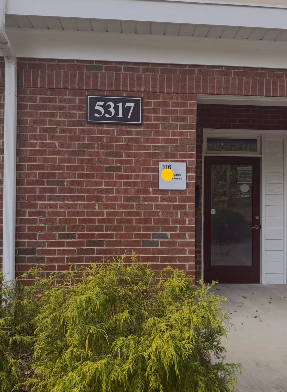 Brick exterior with address plaque 5317, doorway and shrubs in front of the facility.