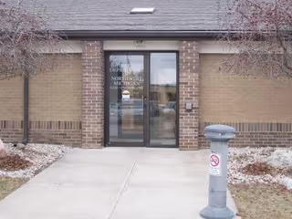 Exterior brick entrance of Health Department of Northwest Michigan with glass doors and walkway.