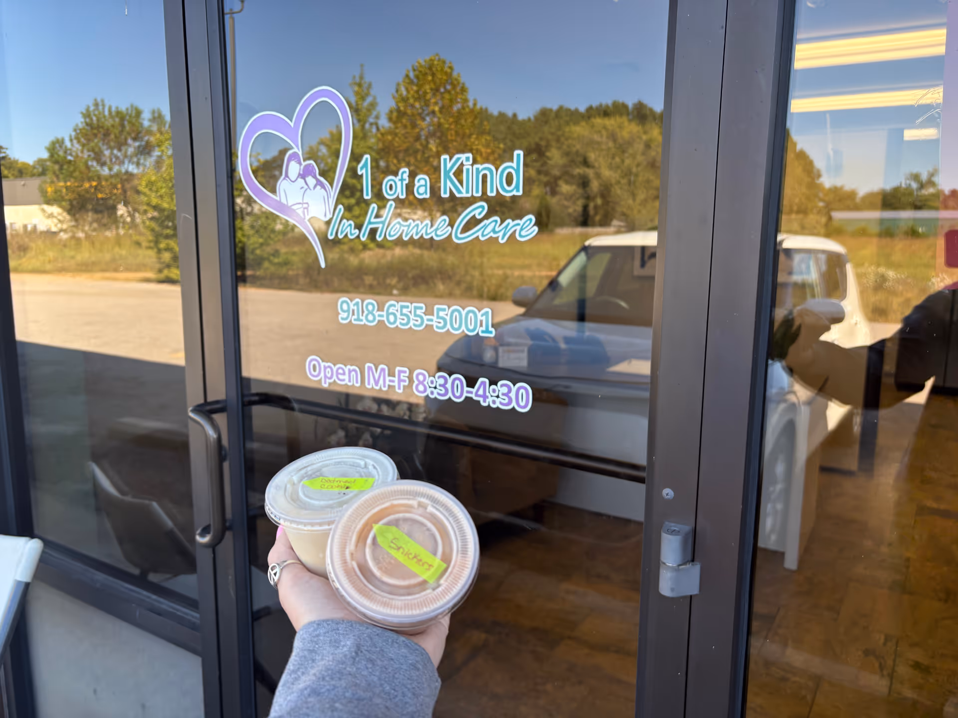Glass entrance door with 1 of a Kind In Home Care logo and cups.