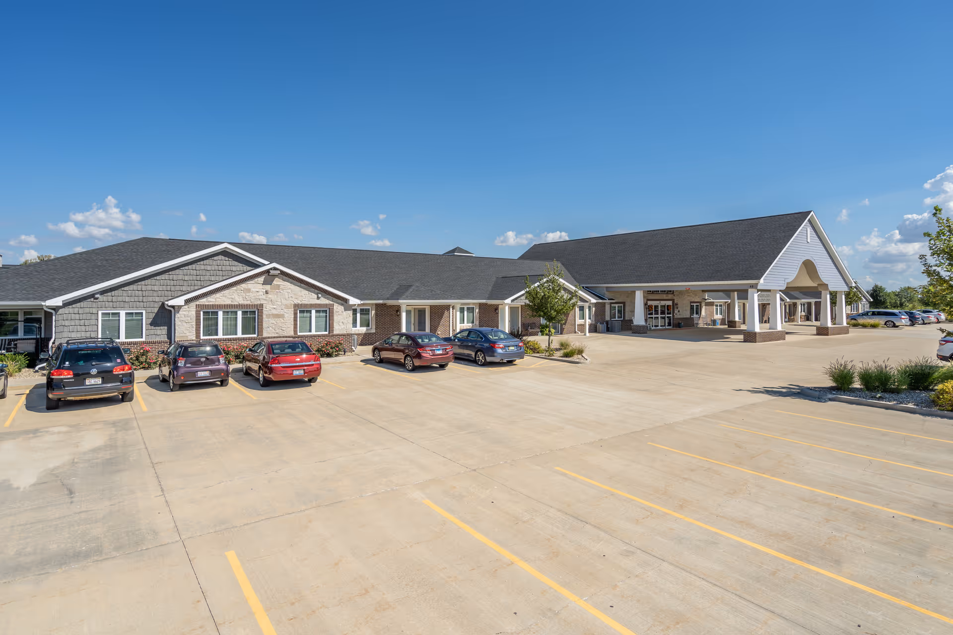 Single-story senior living facility exterior with a front entrance and ample parking.