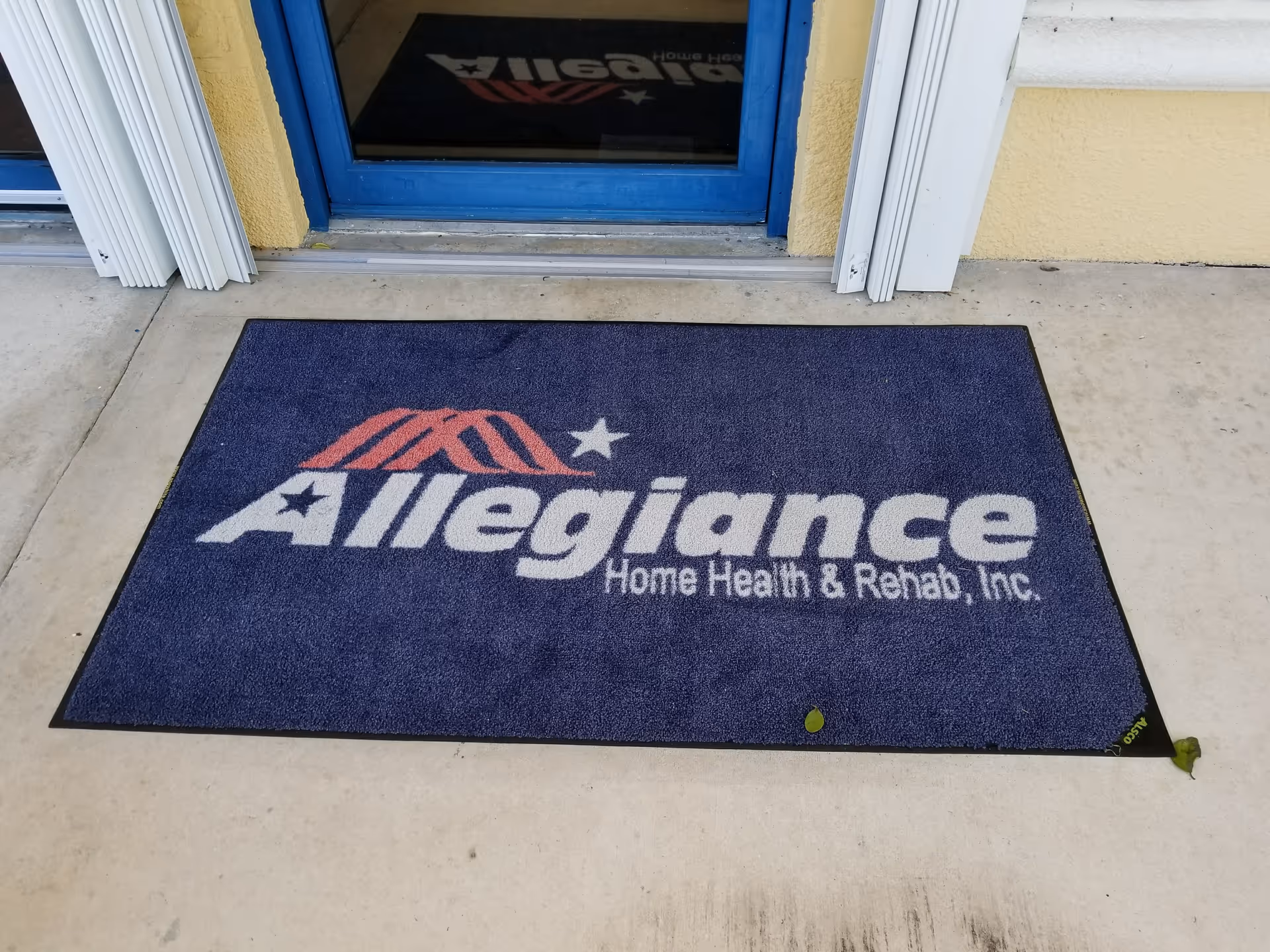 Blue door entrance with an Allegiance doormat displaying Home Health & Rehab logo