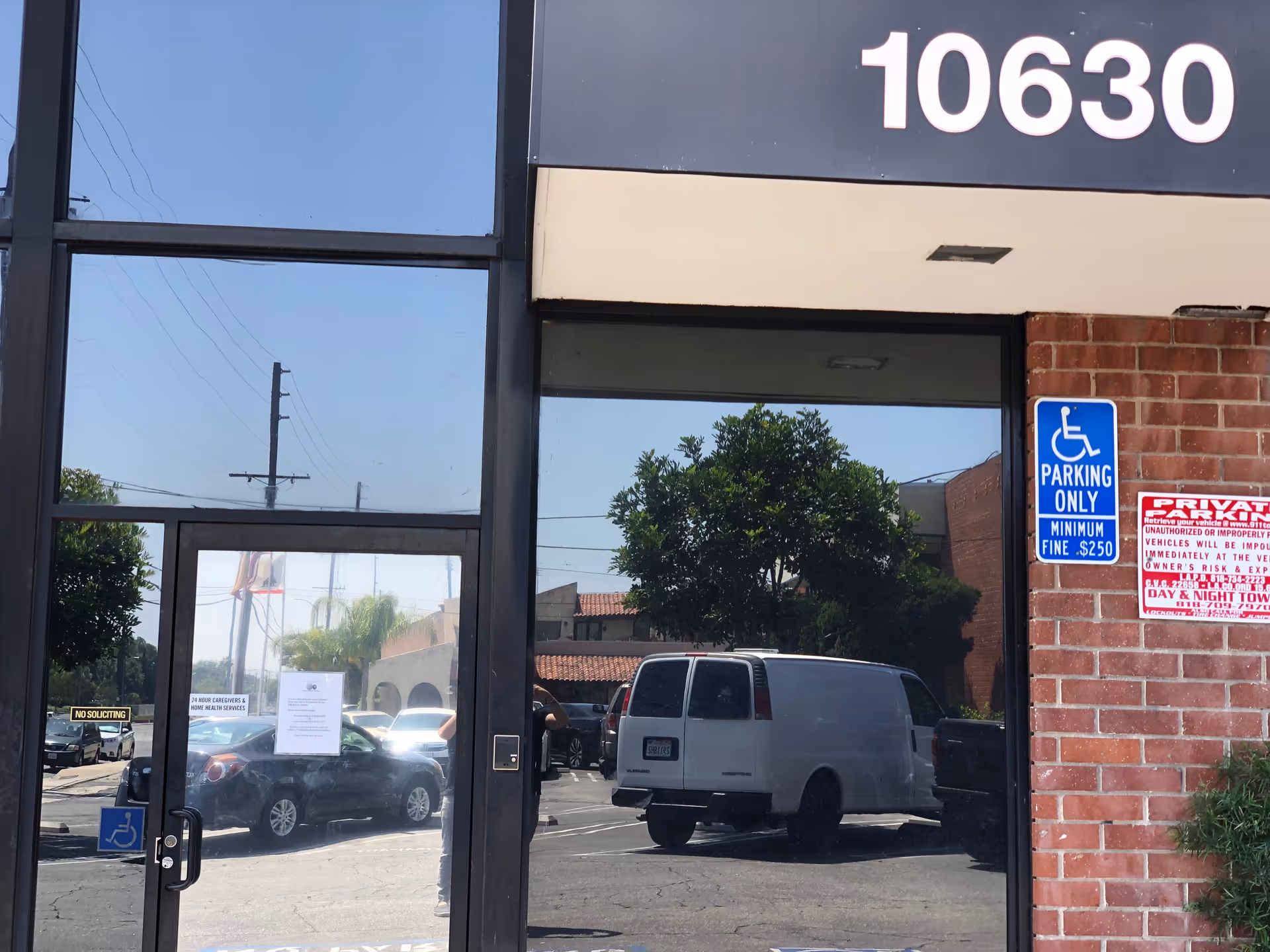 Exterior building with glass doors, brick wall, and handicap parking sign.