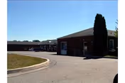 Exterior view of Fair Acres Geriatric Center with a curved driveway and brick entrance.