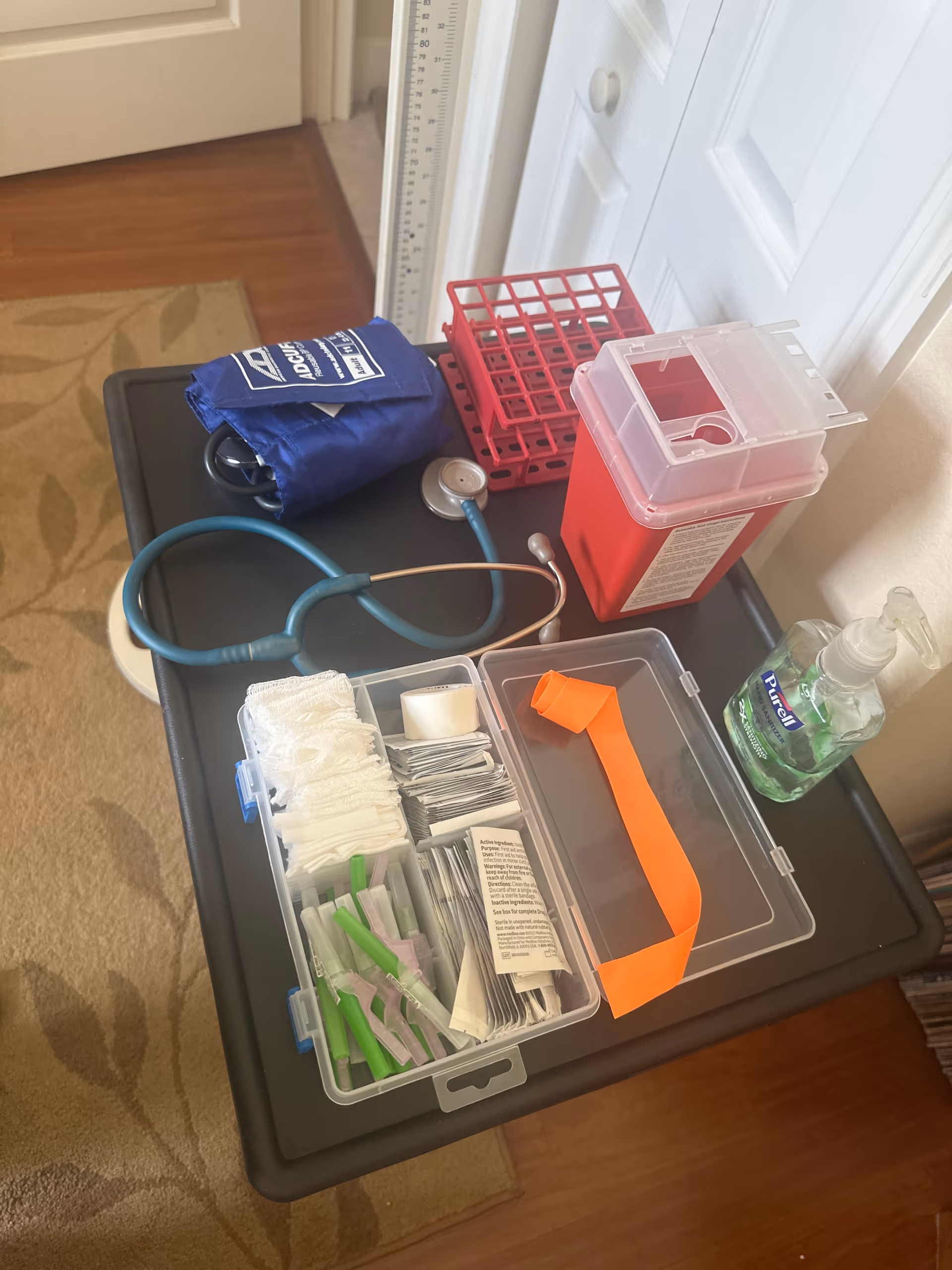 Medical supplies on a cart, including stethoscope, bandages, sharps container, and sanitizer.