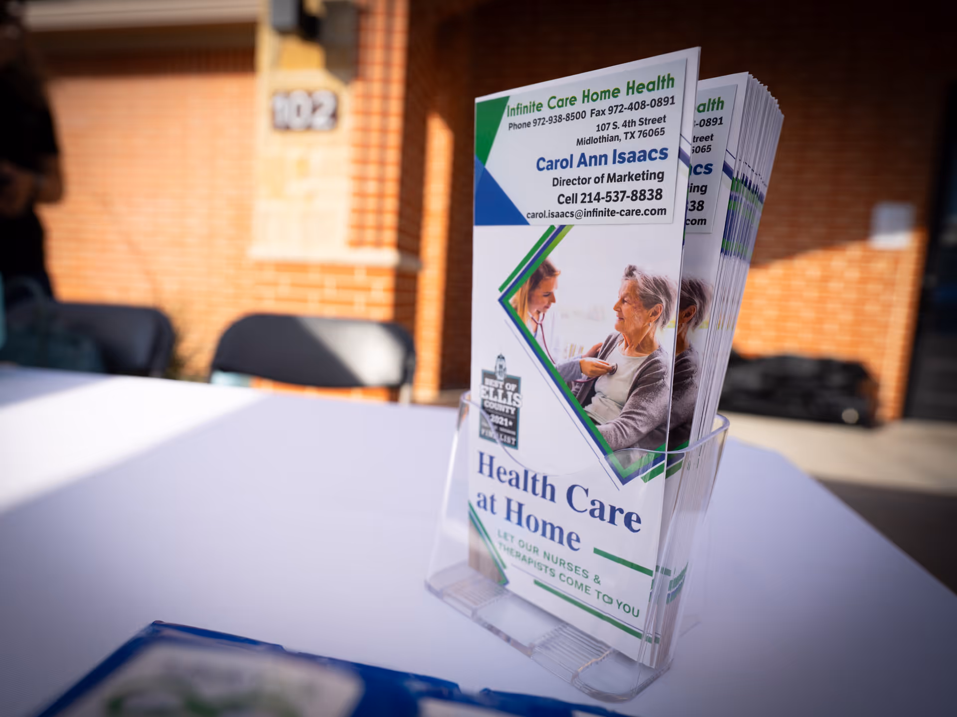 Brochure stack in a clear holder on a table outside Infinite Care Home Health.