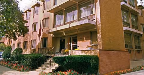 Exterior view of a brick senior living facility with stairs and balconies.