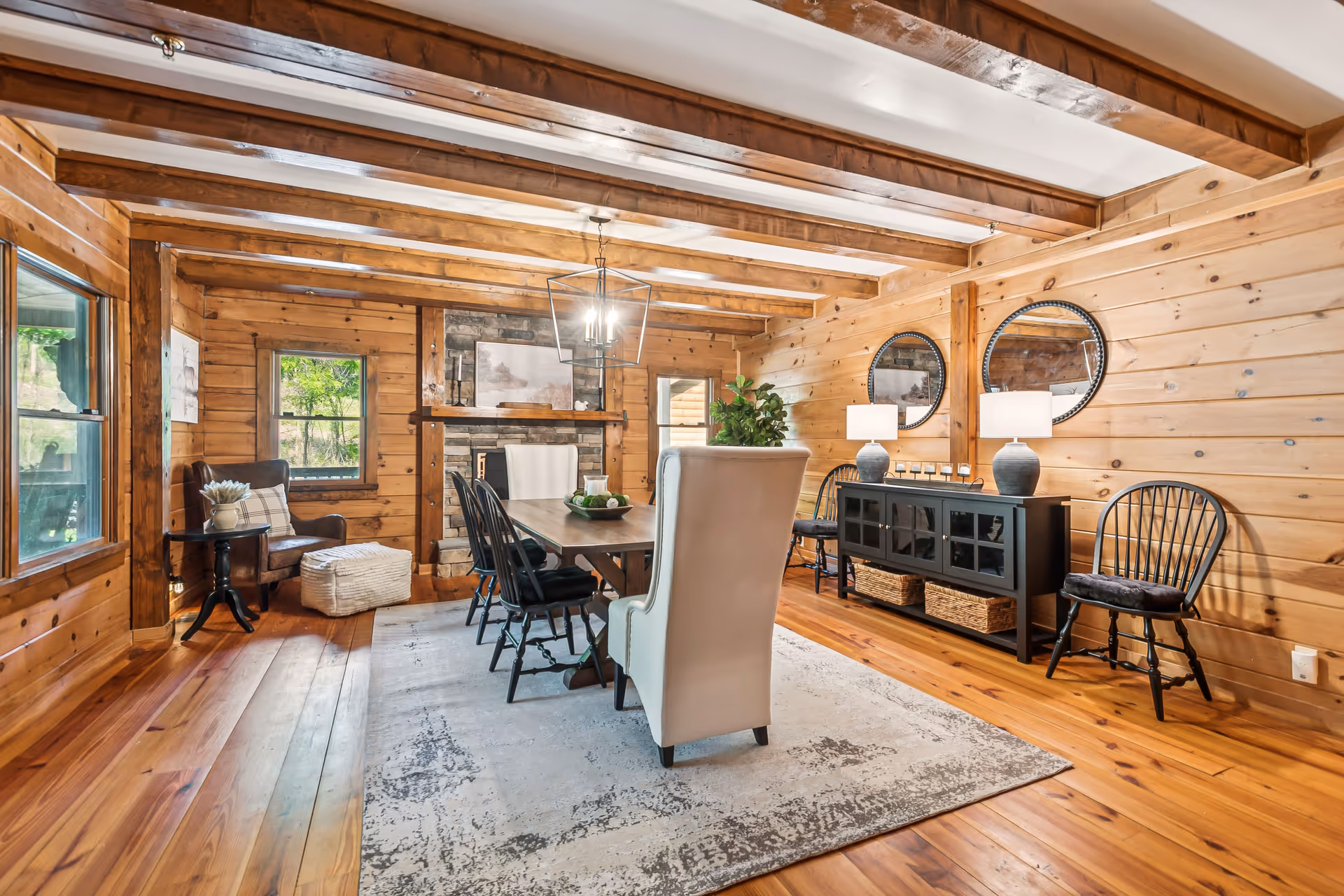 Rustic wooden dining room with a table, chairs, and a sideboard in a cozy wood-paneled space.