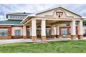 Exterior front view of Chateau Terrebonne Health Care with columns and green lawn.