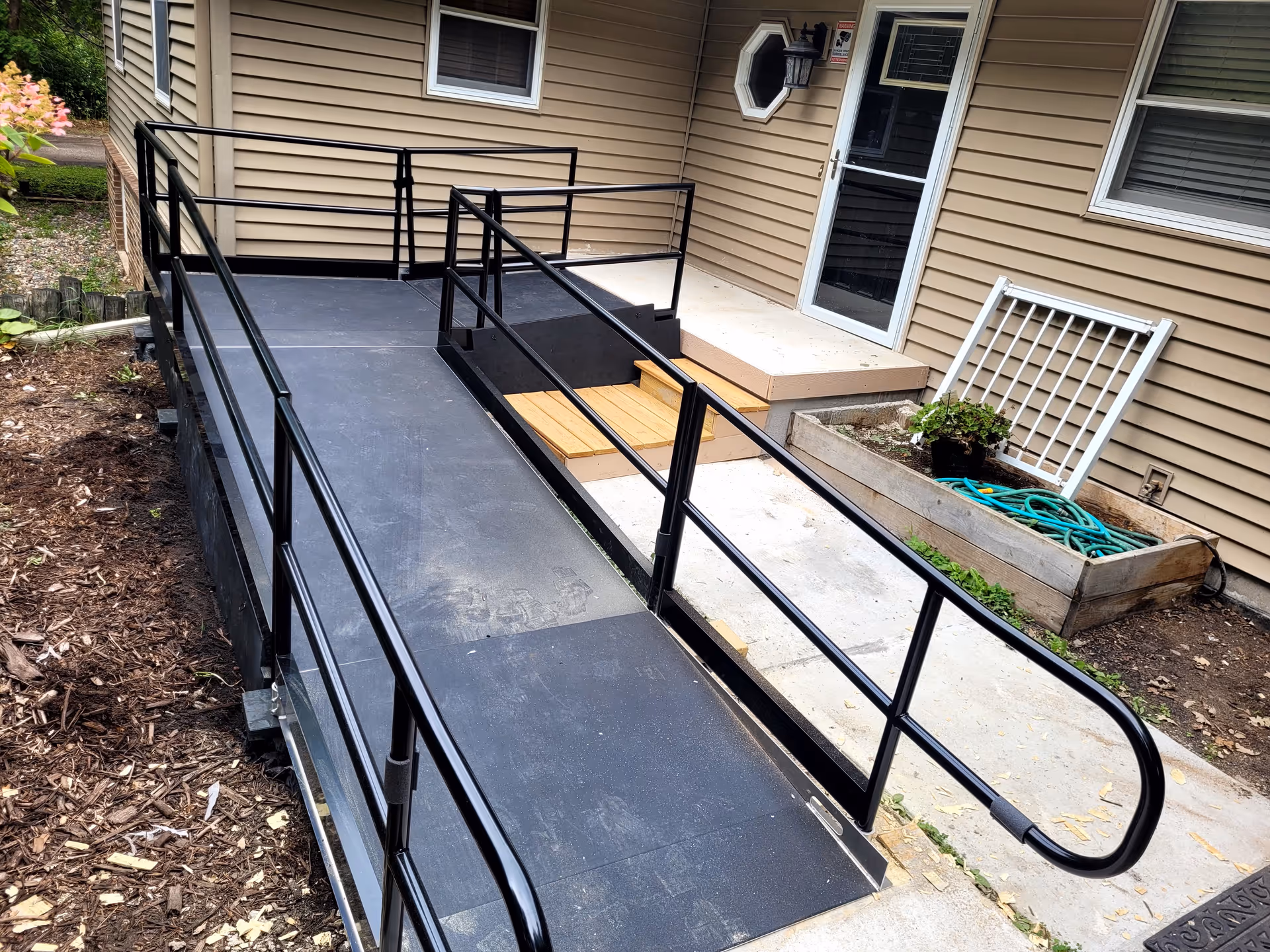 Exterior facility entrance with a black metal ramp and stairs leading to a beige building.