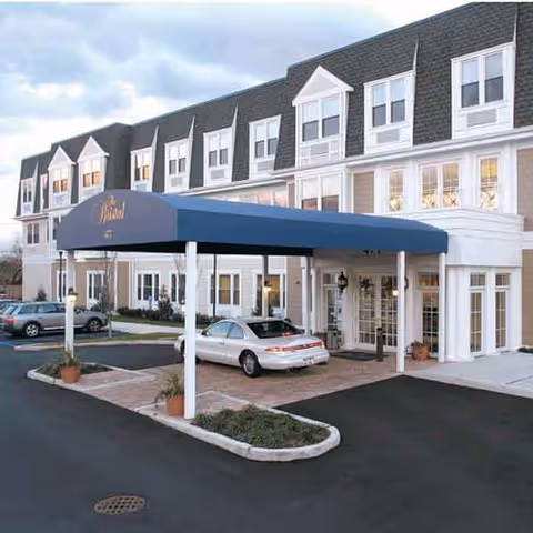 Front view of The Bristal Assisted Living at North Woodmere with a blue canopy entrance.