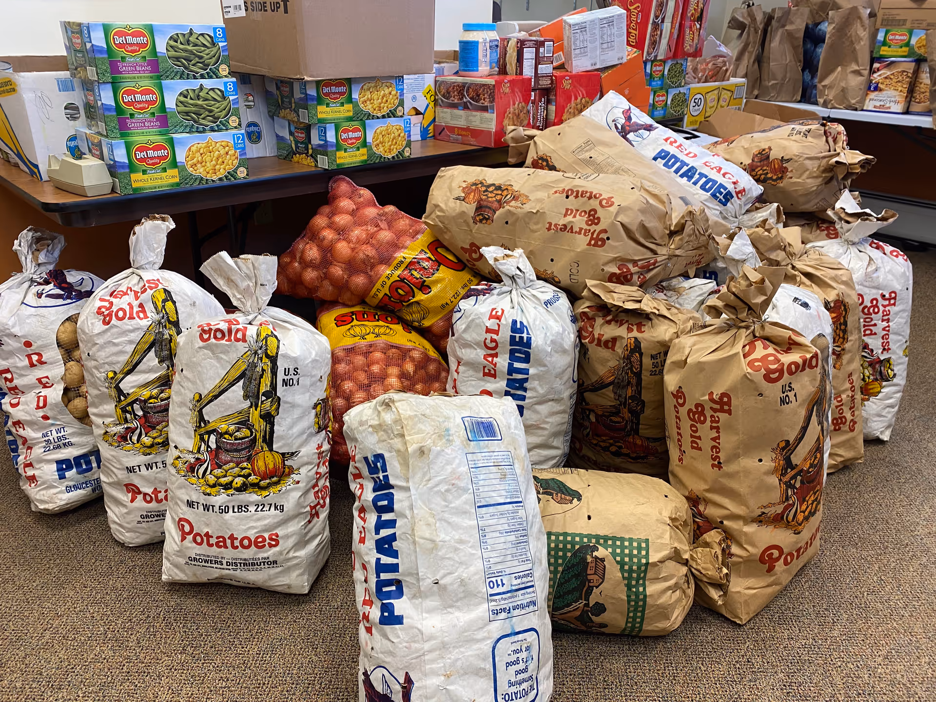 A cluttered indoor storage area with large sacks of potatoes and onions.