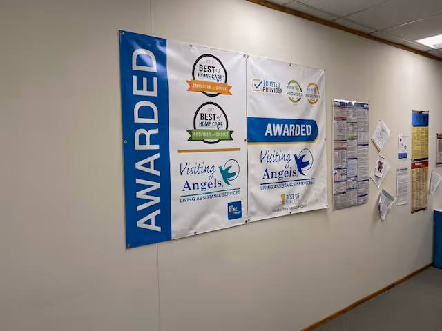 Interior hallway wall with large Visiting Angels banners and notice boards.