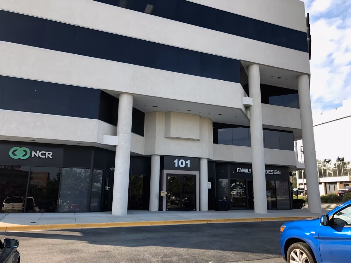 Modern office building exterior with glass storefronts, pillars, and the entrance labeled 101.