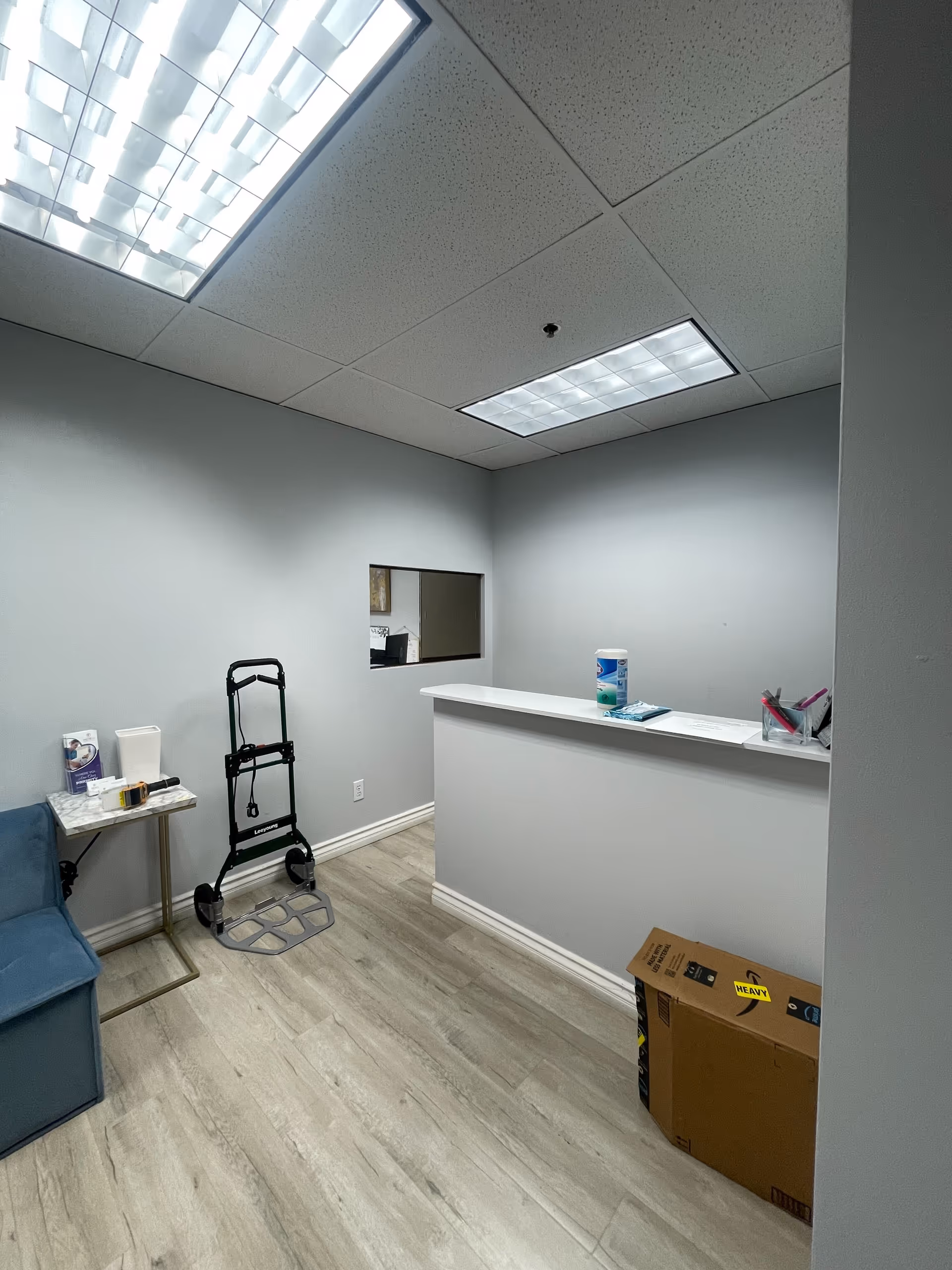 Small interior reception area with a counter, walker, chair, and cardboard box.