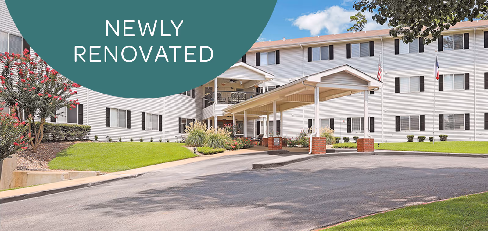 Exterior view of a senior living building with a covered entrance and manicured lawn.