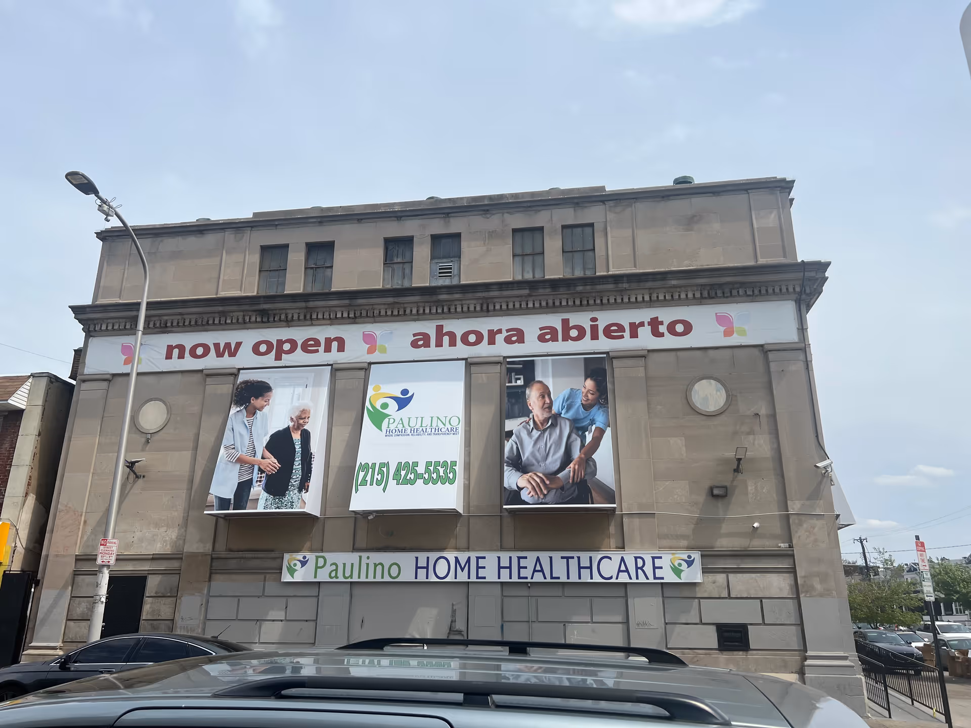 Exterior view of a building with Now Open banners and Paulino Home Healthcare signage.