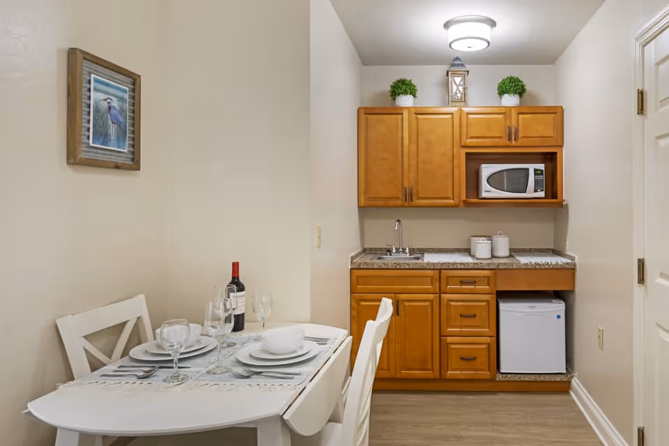 Cozy kitchenette with wooden cabinets, sink, microwave, and small dining table.
