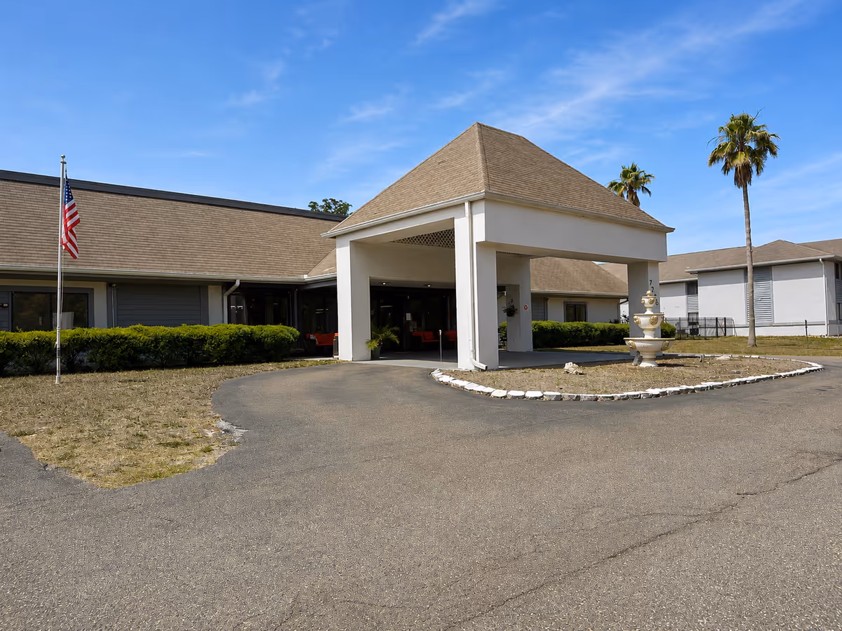 Exterior view of Oakview Terrace entrance with curved driveway, fountain, and palm trees.