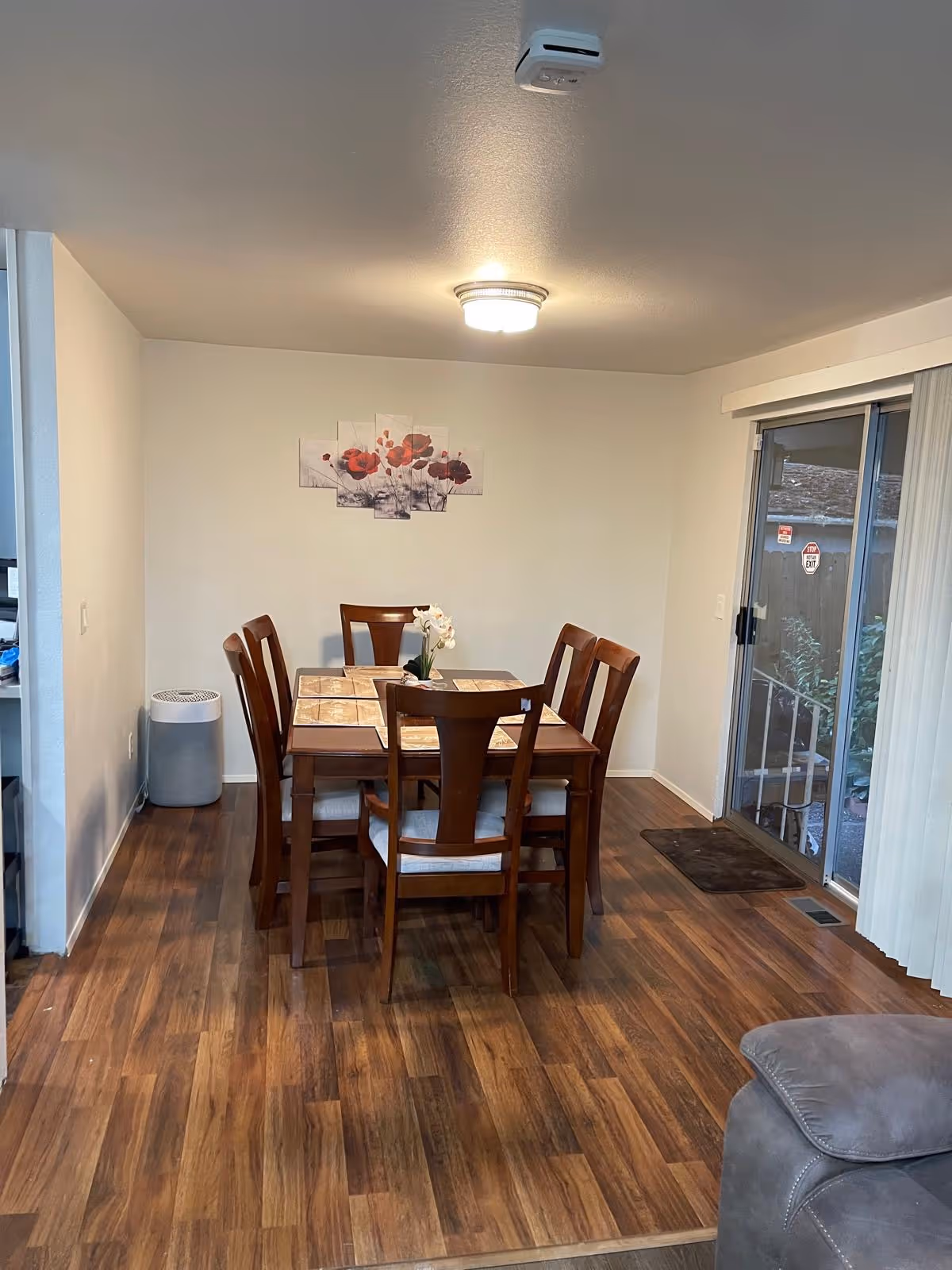Wooden dining table with six chairs in a bright dining room.