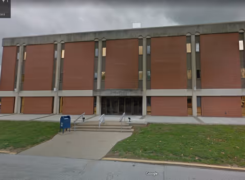 Front view of a brick building with steps and a glass entrance.