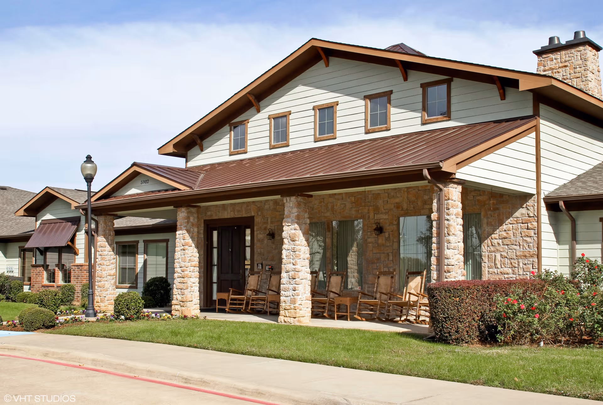 Front exterior of Magnolia Court Assisted Living with stone columns and a covered porch.