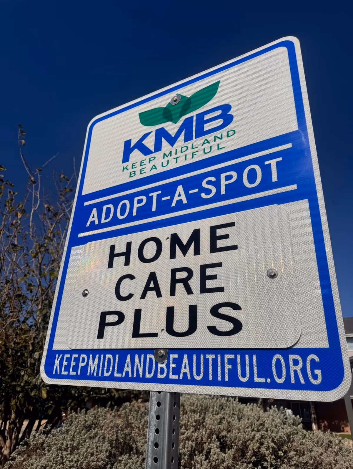 A large outdoor sign for Home Care Plus with Adopt-A-Spot branding and logo.