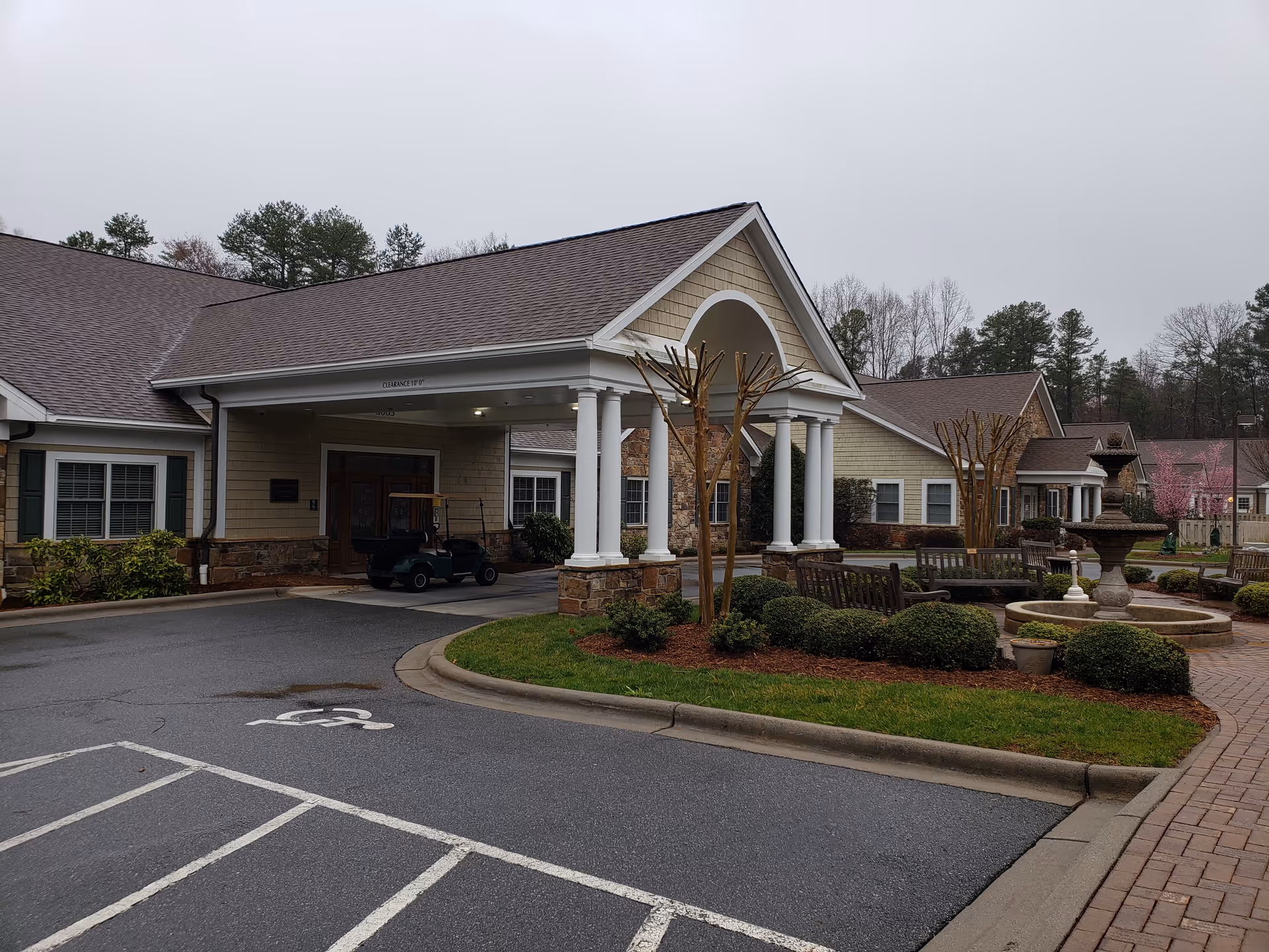 Exterior view of Atrium Health Hospice and Palliative Care Cabarrus with covered entrance, benches, and fountain.