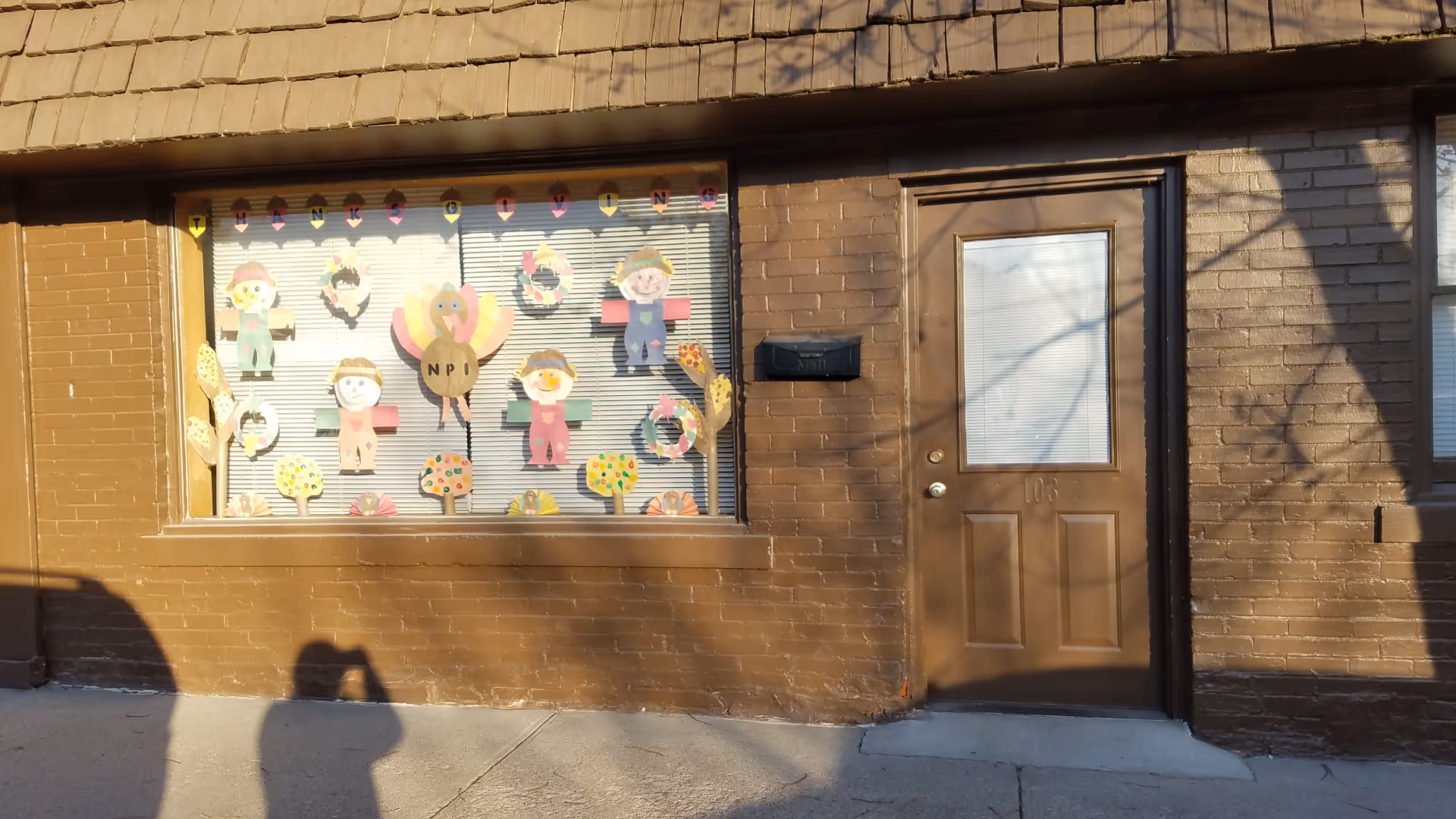 Brown brick building exterior featuring a large decorated window and a brown door.