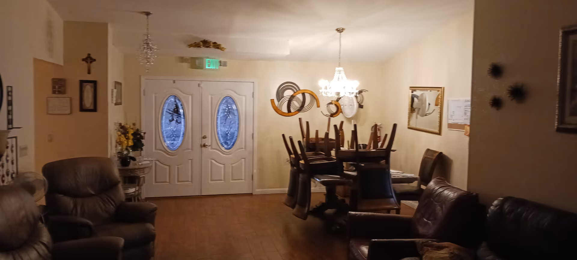 Cozy senior living lounge with leather seating and a dining table near double doors.