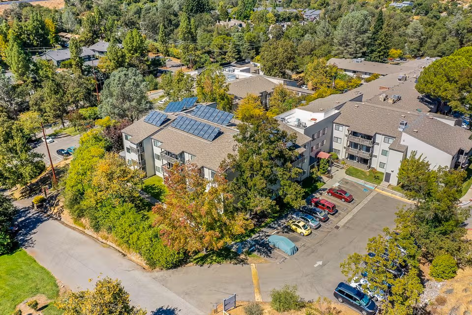 Aerial view of Auburn Ravine Terrace senior living buildings, parking, and trees.