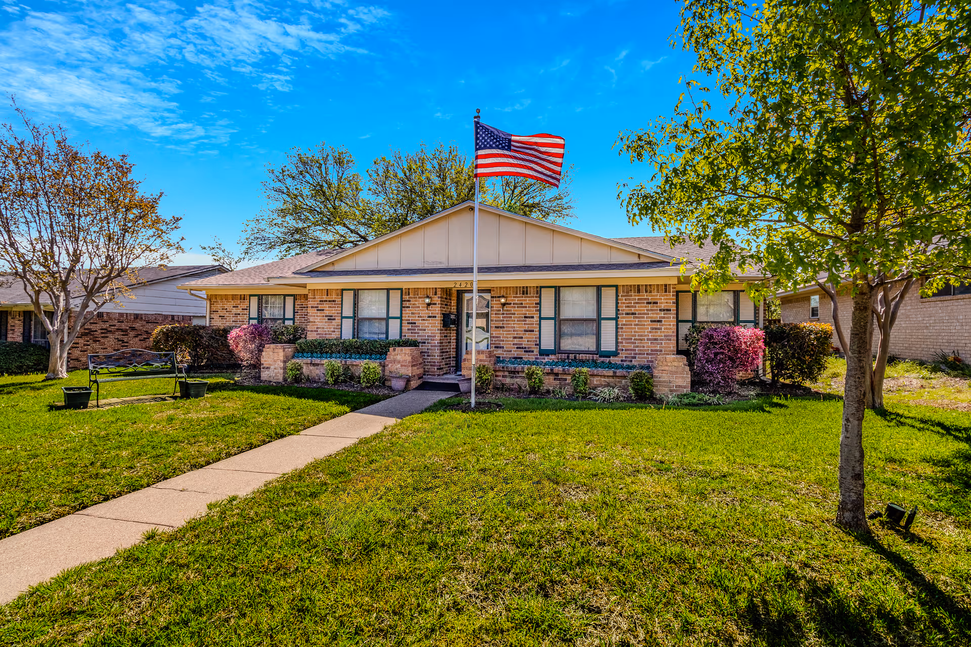 Front view of a brick senior living facility with a flagpole and trees.