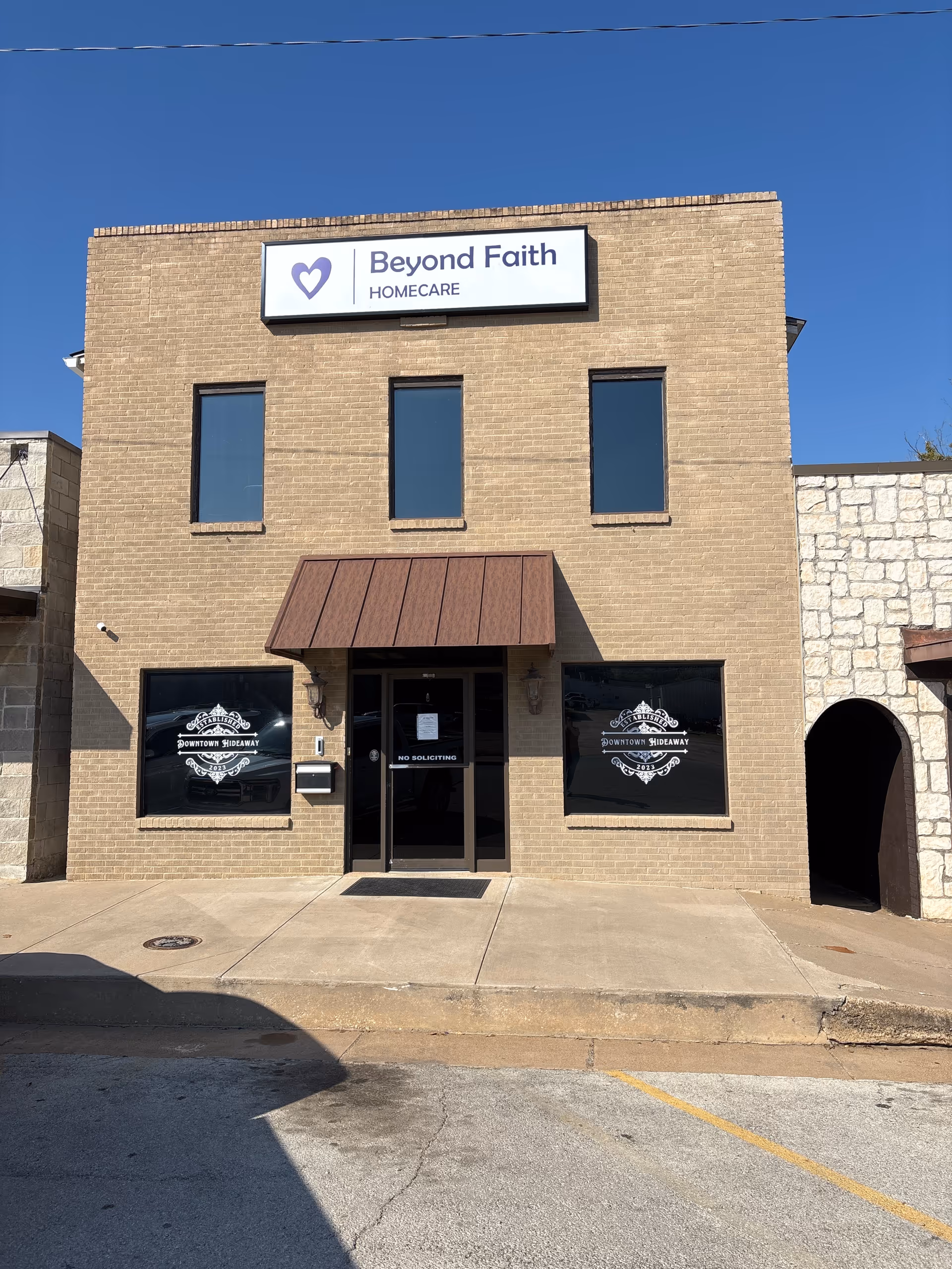 Two-story brick storefront with Beyond Faith Homecare sign and glass doors at entrance.