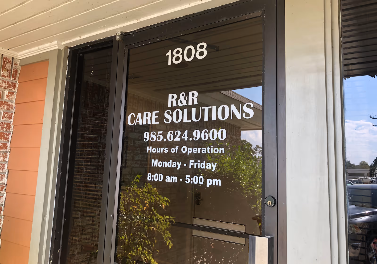 Glass door with address 1808 and R&R Care Solutions sign at building entrance