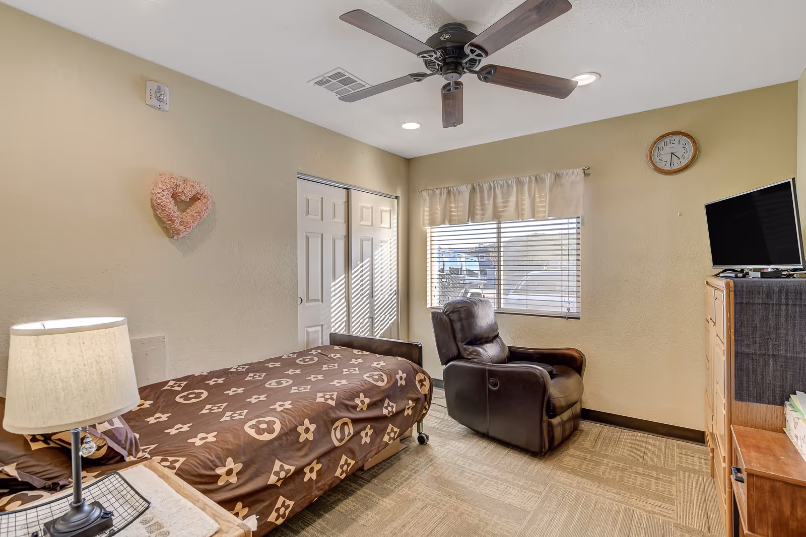Cozy bedroom featuring a bed, leather recliner, dresser, and a window with blinds.
