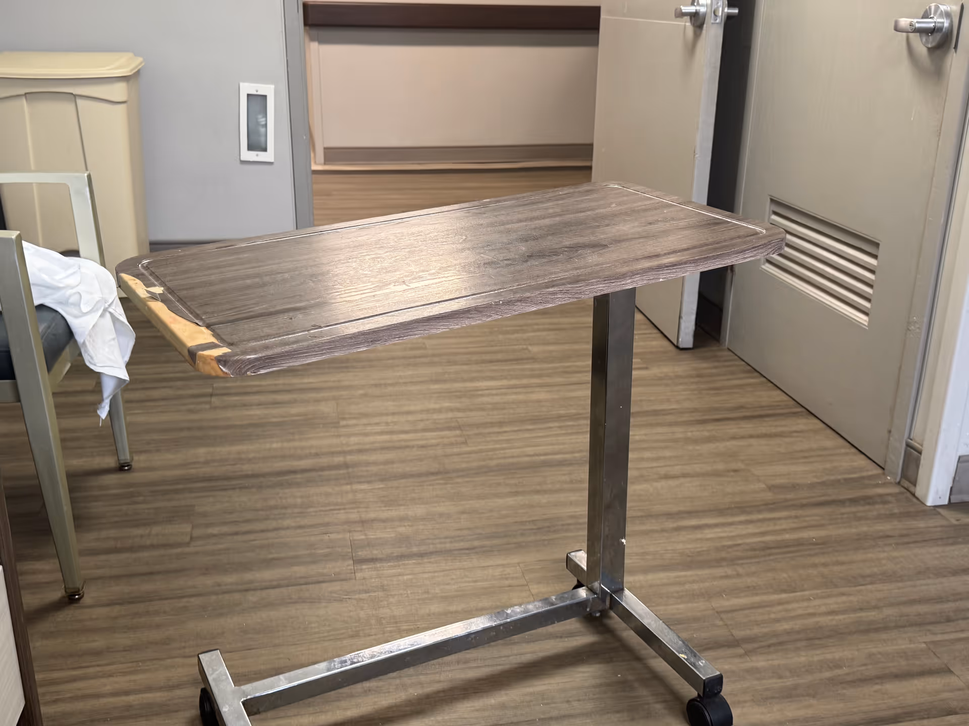 A worn wooden rolling table sits in a senior living facility interior.