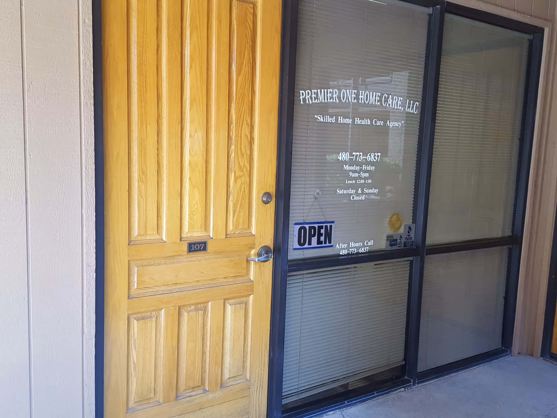 Wooden front door beside glass storefront displaying Premier One Home Care LLC and OPEN sign