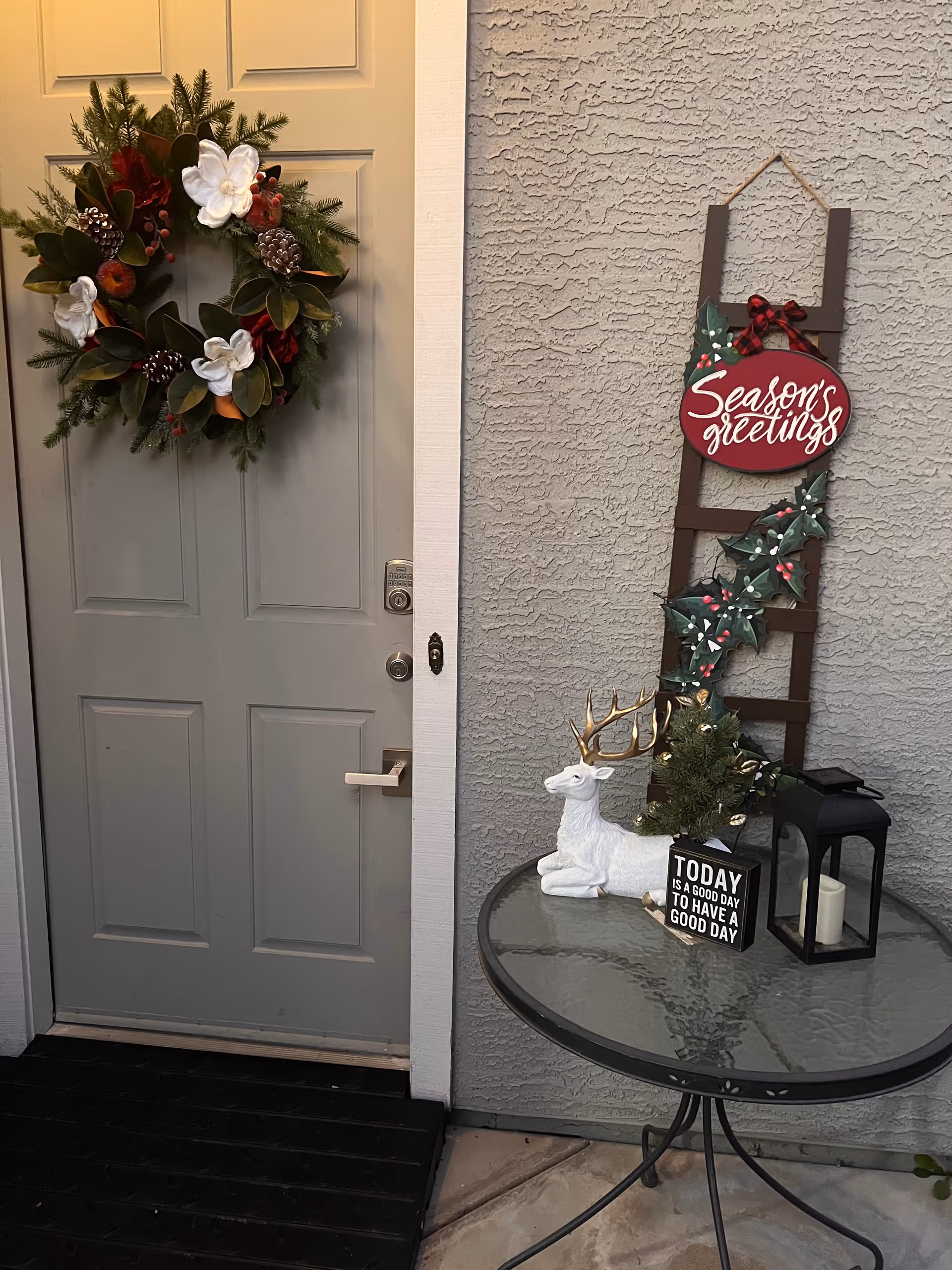 Front entrance features a holiday wreath on the door and seasonal decor by a table.