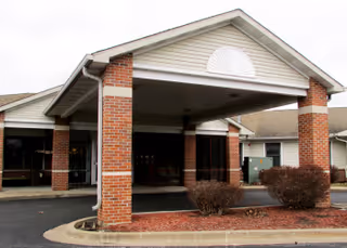 Front exterior of a brick senior living facility with a covered entrance.