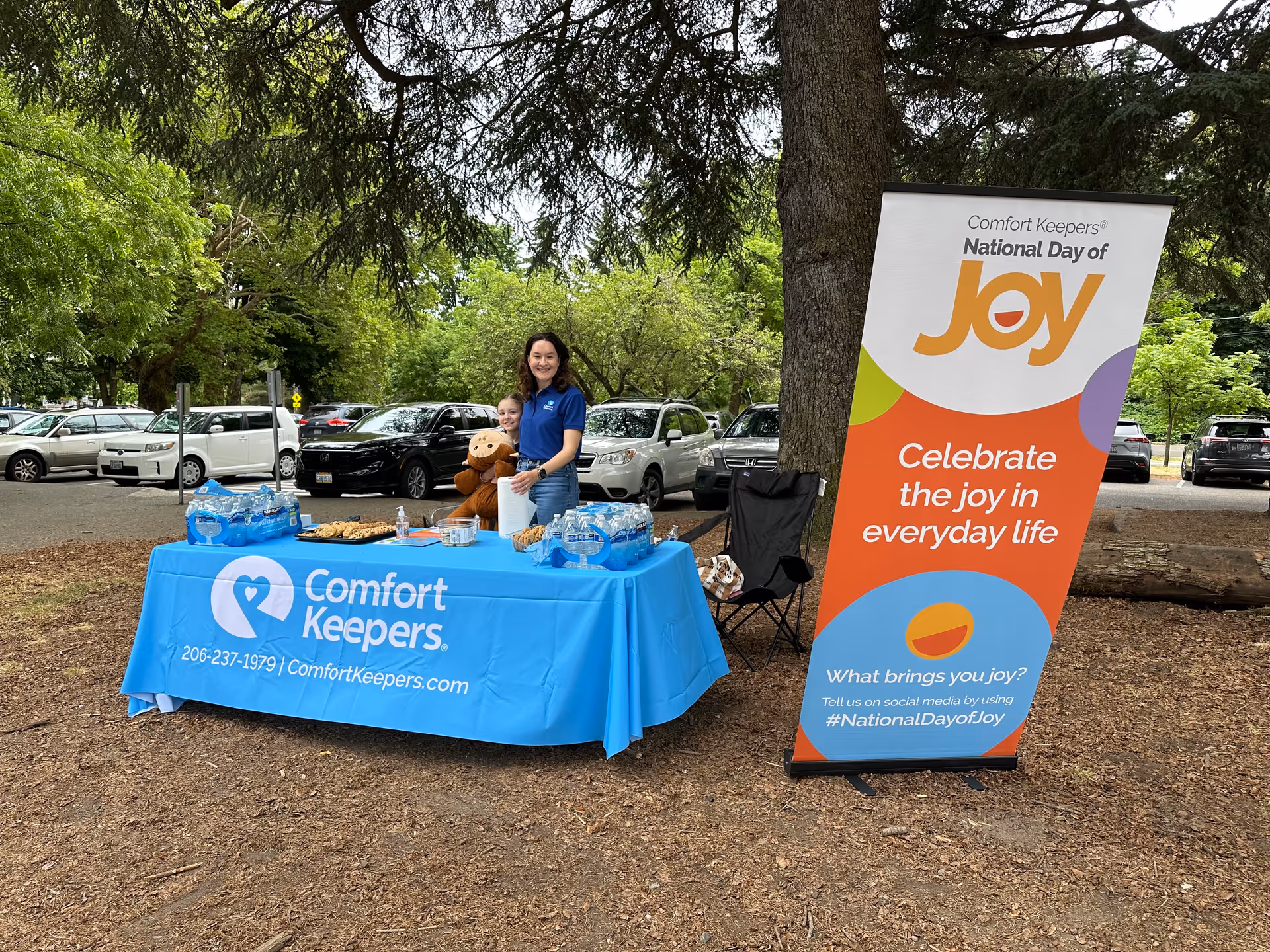 Outdoor event table with Comfort Keepers banner and a staff member.