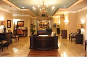 Luxurious lobby with central reception desk, seating areas, chandeliers, and warm decor.