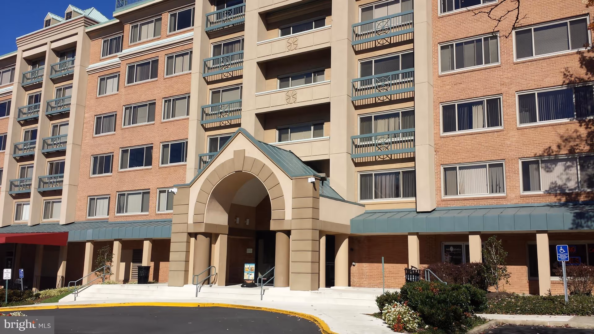 Exterior of a multi-story senior living building with arched entrance and balconies.