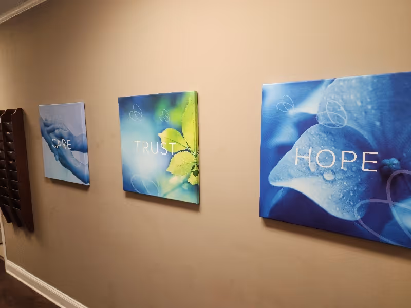 Cream hallway with three blue canvas wall art reading CARE, TRUST, and HOPE.