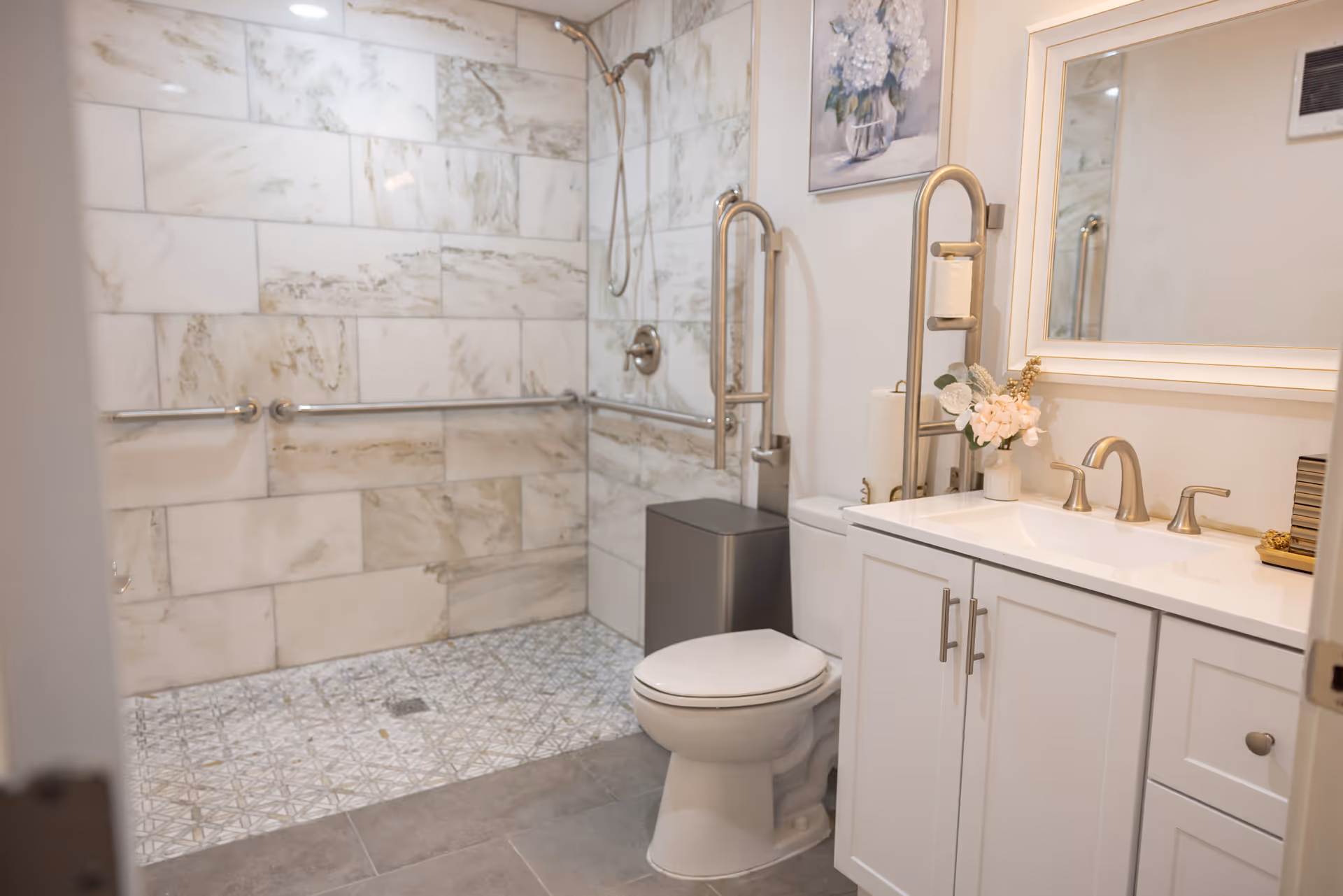 Accessible bathroom featuring a walk-in shower with grab bars and a white vanity.