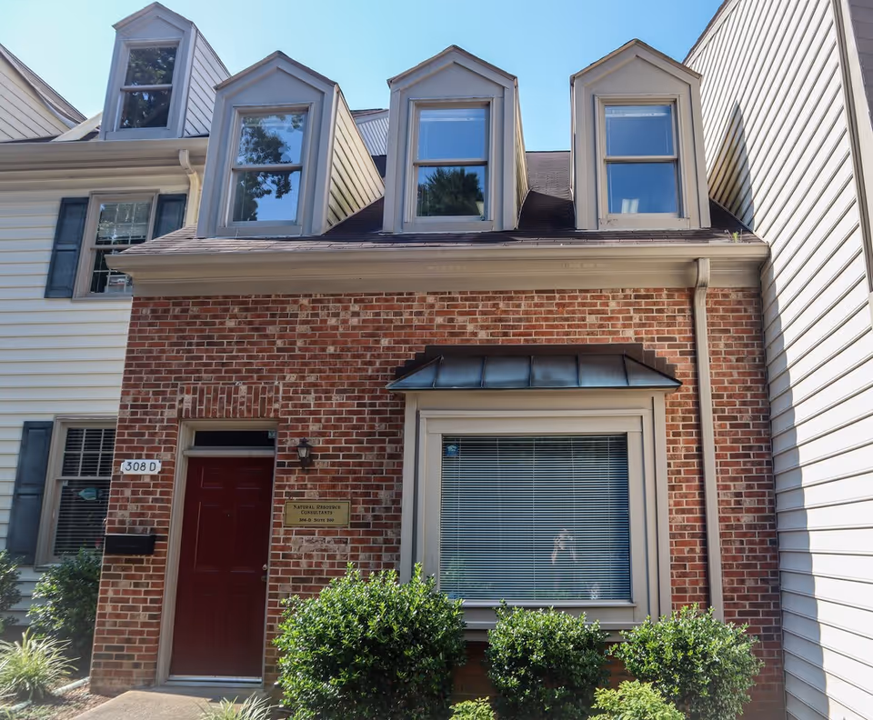 Brick townhouse exterior with dormers and a red front door.