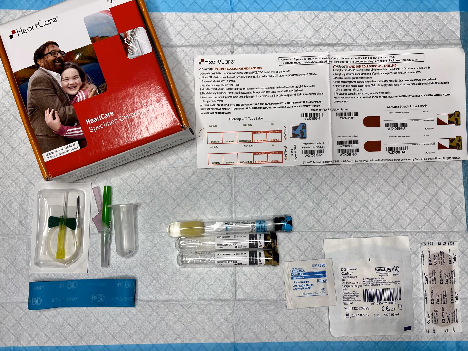 Flat lay of a HeartCare specimen collection kit with syringes and labels on a medical sheet.